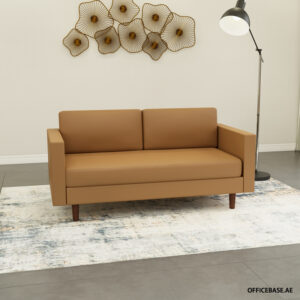 Tan two-seat sofa with clean lines and wooden legs in a minimalist living room, paired with a light patterned rug and a tall floor lamp nearby.