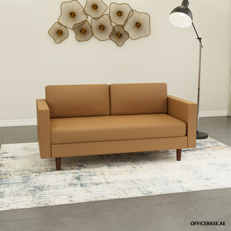 Tan two-seat sofa with clean lines and wooden legs in a minimalist living room, paired with a light patterned rug and a tall floor lamp nearby.