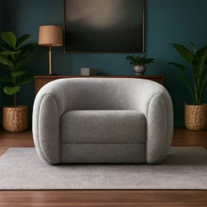 Rounded gray boucle armchair on a light rug in a modern living room with teal walls and potted plants.