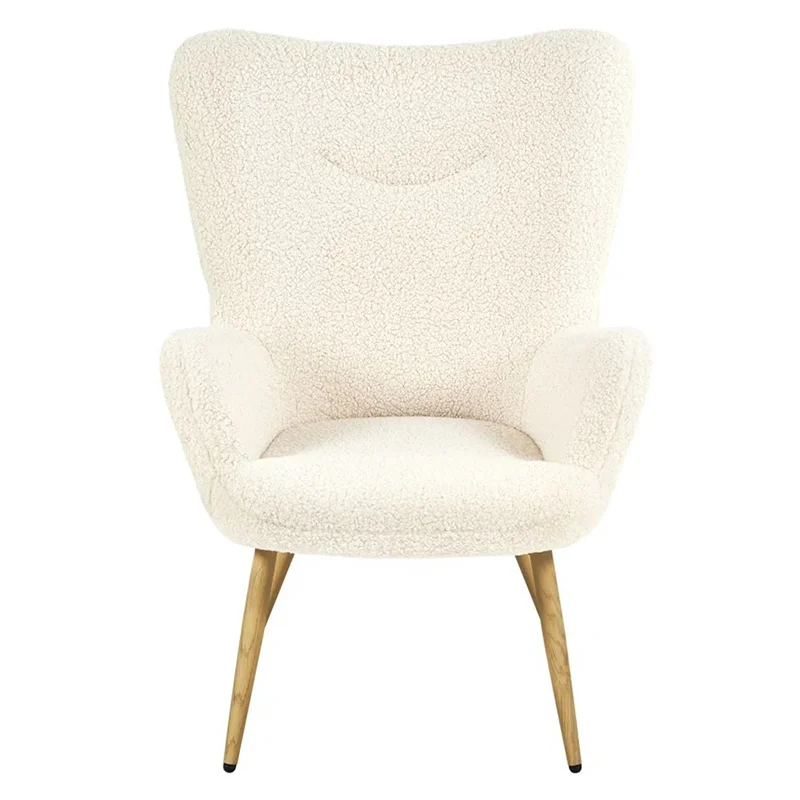 White boucle armchair with wooden legs in a cozy bedroom/living area next to a wooden cabinet and lamp, with botanical prints on the wall and a textured rug.